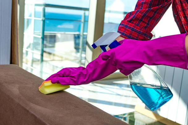 Lastik eldiven ev hanımı bir bez ve sprey ile mobilya toz silerek evi temizliyor. Ev işleri - Fotoğraf, Görsel