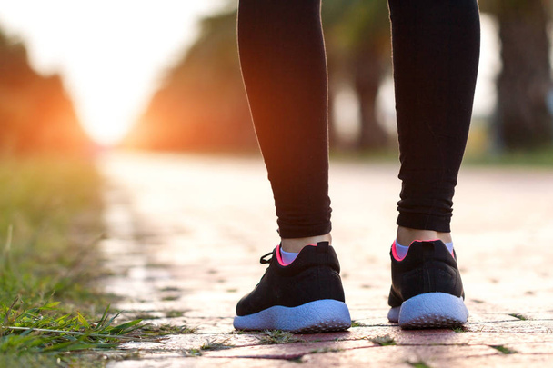 junge, fitte Frau in Turnschuhen, die bei Sonnenuntergang Sport treibt und joggt. Sportlicher Lebensstil - Foto, Bild