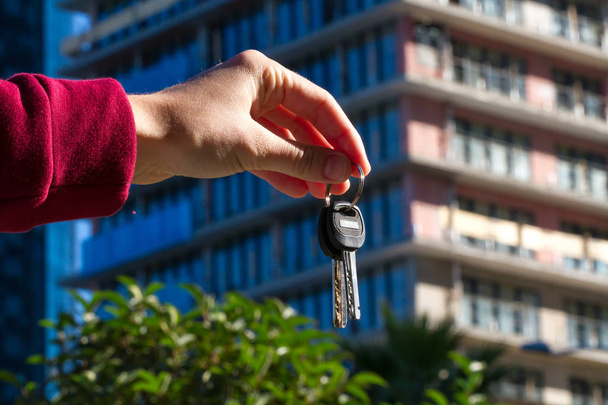 The keys in hand on the background of a multi-storey, apartment building. Real estate investment. Apartment purchase - Photo, Image