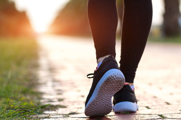 Fiatal, fitnesz nő tornacipőben sportedzéssel és kocogással foglalkozik naplementekor. Sportéletmód - Fotó, kép