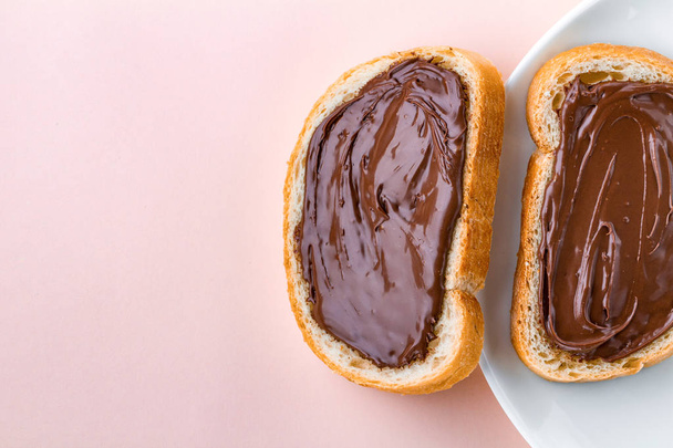 Pieces of long loaf with chocolate, nut paste on a plate. Nut chocolate cream sandwiches on a breakfast. Top view. Copy space  - Foto, Imagen