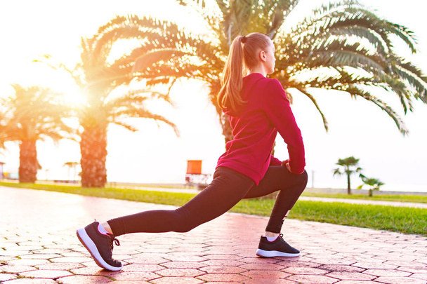 Nuori, kunto nainen lenkkarit ja urheiluvaatteet tekee venyttely lihaksia ennen urheilukoulutusta ja lenkkeily. Urheilu elämäntapa
 - Valokuva, kuva