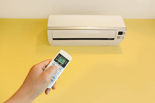 Hand turning on home air conditioning system at 25 degree, energy saving - Photo, image