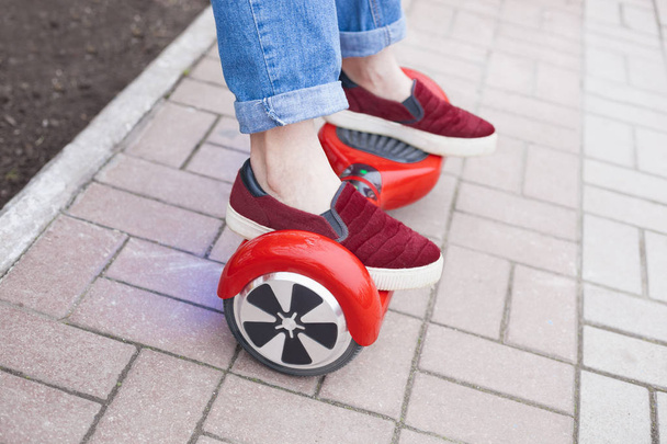クローズ アップ現代赤い電気ミニ セグウェイやホバー ボードのスクーターに乗ってマルサラの靴の女の子の足に。そんなに楽しさと簡単に乗るには、大気中に汚染を生成しない新しい輸送の技術の傾向. - 写真・画像