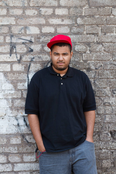 Young black man posing at the grey brick wall on his block - 写真・画像