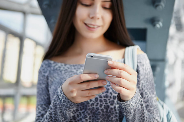 Happy young female using modern silver smart phone. Trendy mobile gadget in focus - 写真・画像