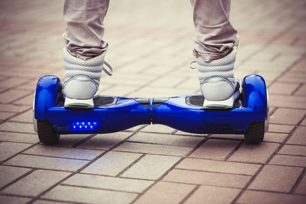 Person riding a modern blue electric mini segway or hover board scooterin outdoors. Popular new city transport that is easy and fun to ride and makes no air pollution to the atmosphere  - Photo, Image