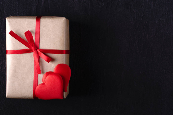 Valentines, Mothers or Womens Day holidays preparations. presents, celebration concept. composition with gift box, festive heart shaped decorations and empty black background, copy space - Fotoğraf, Görsel