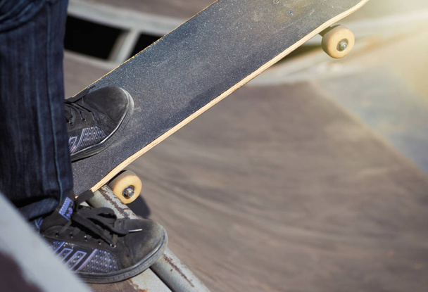 Legs of a female skater on top coping of a ramp ready to roll-in and do tricks - Photo, image