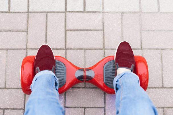 Close up on feet of a gir in marsala shoes riding on a modern red electric mini segway or hover board scooter. Trending new transportation technology that is so much fun and easy to ride and produces no air pollution to the atmosphere. - Foto, immagini
