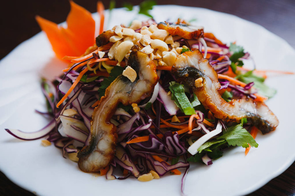 Delicious Asian salad with red cabbage & eel stripes on white plate.Tasty Vietnamese saald close up.Colorful Chinese ingredients for healthy eating. - Photo, image