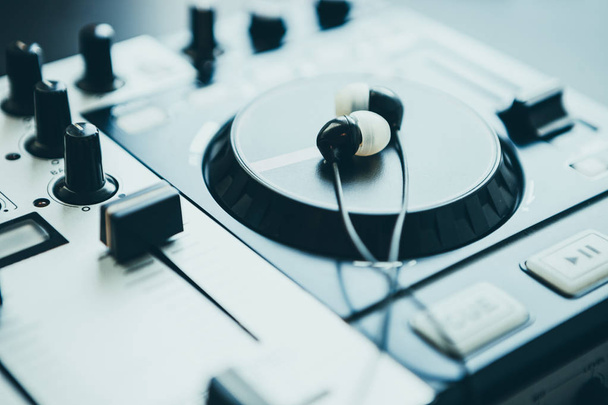 Headphones on DJ midi controller turntable. Close up on sound equipment. Knobs, fader, jog wheel - Fotó, kép