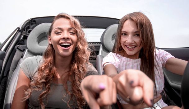 two happy girls sitting in the car and pointing at you - Foto, immagini