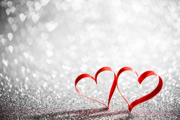 Two red ribbon hearts on glowing bokeh lights background - 写真・画像