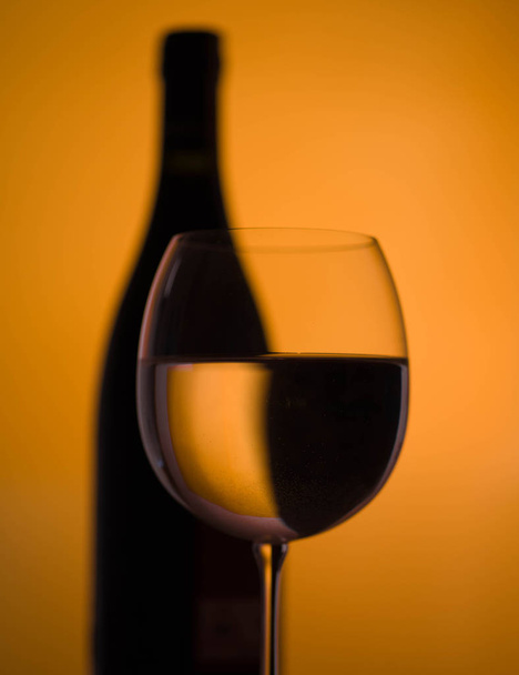Wine glass and bottle on orange background  - Photo, Image