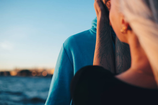 Girl holding young man's face, couple in love on pier, sunset time, selective focus - Foto, immagini