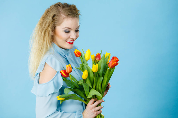 International women day, eight march. Beautiful portrait of pretty woman blonde hair with red yellow tulips, fashion make up, elegant dress. Mother day. On blue - Fotó, kép