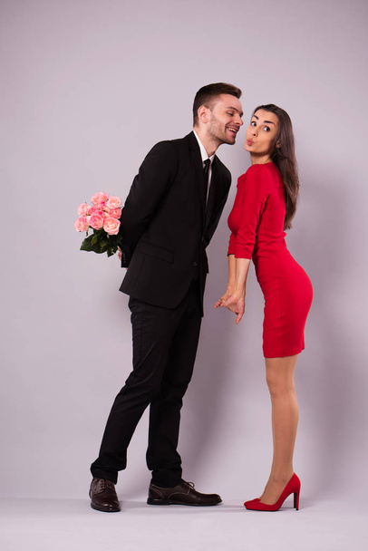 Love you so much! Beautiful stylish and elegant couple in suit and dress are hugging, have a fun and posing isolated in studio. Holidays and events. St Valentine's day. Day of lovers - Foto, imagen