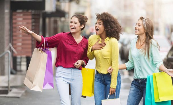 Mulheres felizes com sacos de compras andando ao longo da rua da cidade
 - Foto, Imagem
