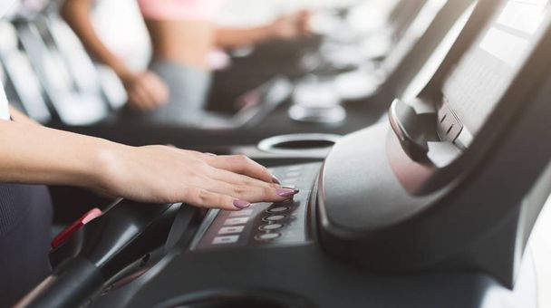 Woman adjusting speed on treadmill, training in gym - Photo, Image
