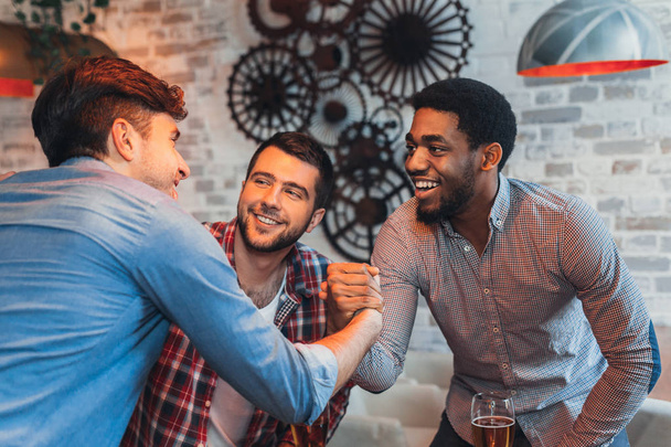 Amis multiraciaux se saluant dans un pub de bière
 - Photo, image