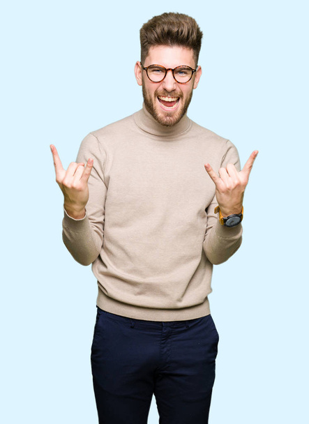 Mladý pohledný obchodní muž nosí brýle křičí s šílený výraz dělá rock symbol s rukama. Hudební hvězda. Těžký koncepce. - Fotografie, Obrázek