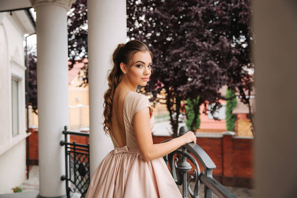 Young model with great evening dress stand by the restaurant. Brunette girl has beautiful hair style and makeup - Foto, immagini