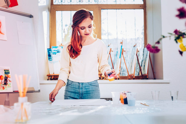 Art teacher wearing jeans and beige shirt standing in painting studio - Φωτογραφία, εικόνα