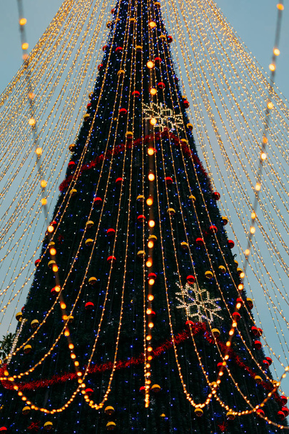 Nahaufnahme von Christbaumkugeln und Schneeflockengirlanden, die an der Tanne am Stadtplatz hängen - Foto, Bild