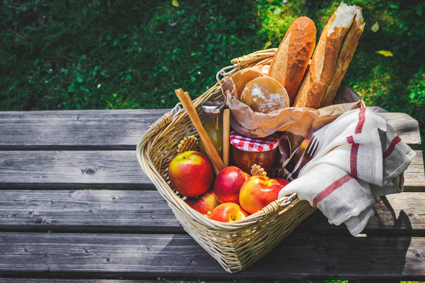 Picnic basket filled with fruit , bread and jar with apricot jam - Фото, изображение