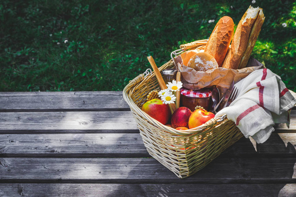 Picnic basket filled with fruit , bread and jar with apricot jam - Foto, imagen