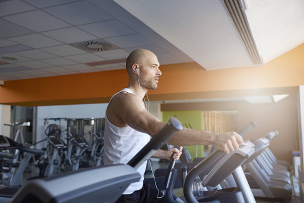 Sporty man is working out in gym. Doing cardio training on treadmill. Running on treadmill. - Fotoğraf, Görsel