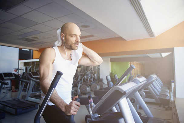 Sporty man is working out in gym. Doing cardio training on treadmill. Running on treadmill. - Foto, Imagem