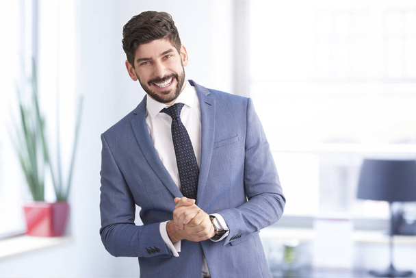 Portrait of cheerful young businessman wearing suit and tie while standing in the office.  - Foto, Bild