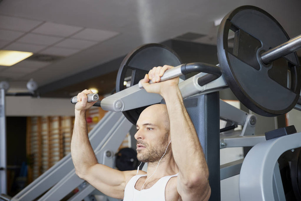 Close-up of man in the gym doing dumbbell exercises to create more muscular body. - Foto, imagen