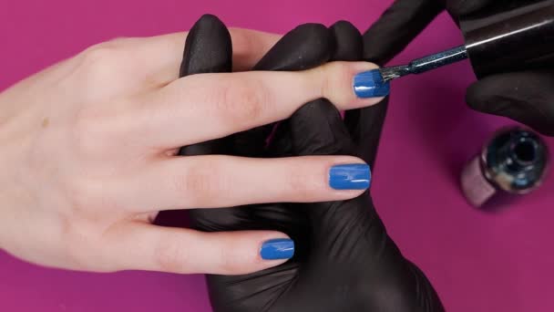 Βαφές μανικιουρίστα πελάτες νύχια με βερνίκι νυχιών μπλε απόχρωση στο κόκκινο φόντο, μακιγιάζ και τα νύχια, κοντινό πλάνο εφαρμόζοντας βερνίκι νυχιών - Πλάνα, βίντεο