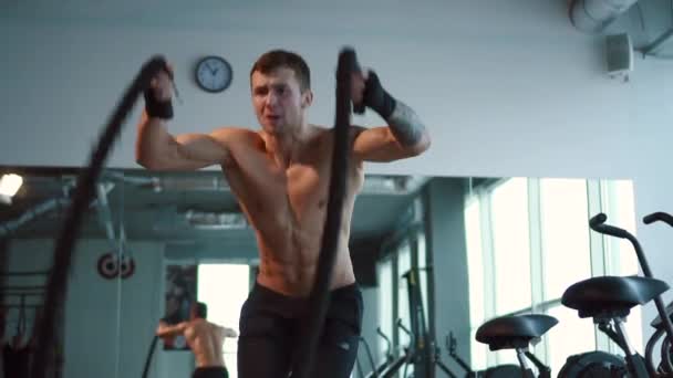 Silný muž pracuje s bojovými provazy v tělocvičně - Záběry, video