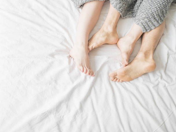 Feet of two couple sleeping on bed under blanket. Love and relationship concept - Foto, imagen