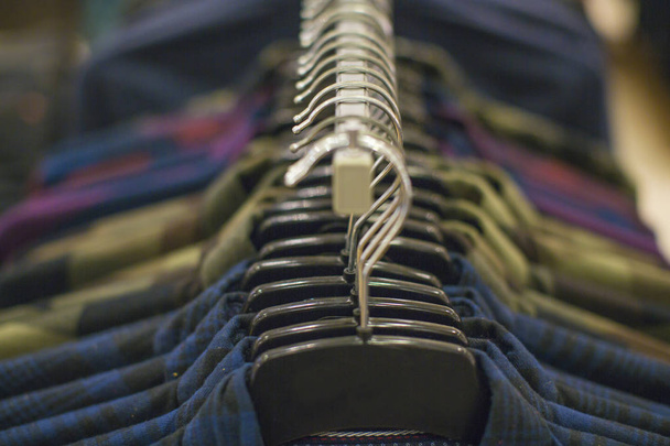 I vestiti sono appesi su uno scaffale in un negozio di abbigliamento di design. Shopping e concetto di vendita
. - Foto, immagini