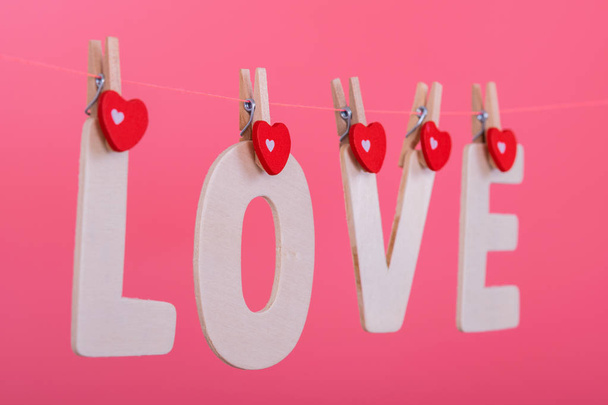 Word LOVE hang on pink color background, valentine - Foto, imagen