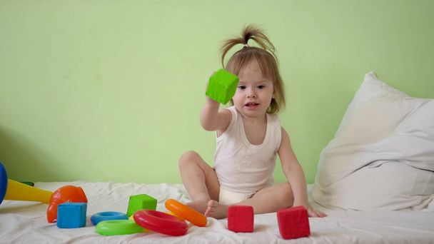 enfant joue avec des cubes multicolores sur un lit blanc et les jette à sa mère. Jouets éducatifs pour enfants d'âge préscolaire et maternelle. Jouet pour enfant
. - Photo, image