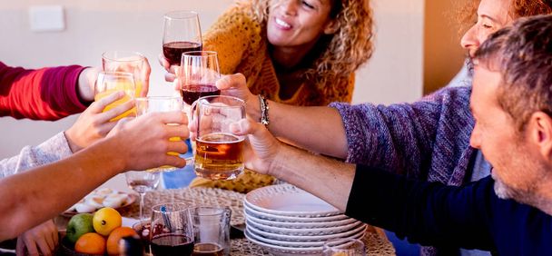 Group of caucasian people friends cheering with glasses of beer and wine all together celebrating and having fun outdoor at home with smiles and laughs - horizontal image with party and lunch in friendship concept - Photo, image