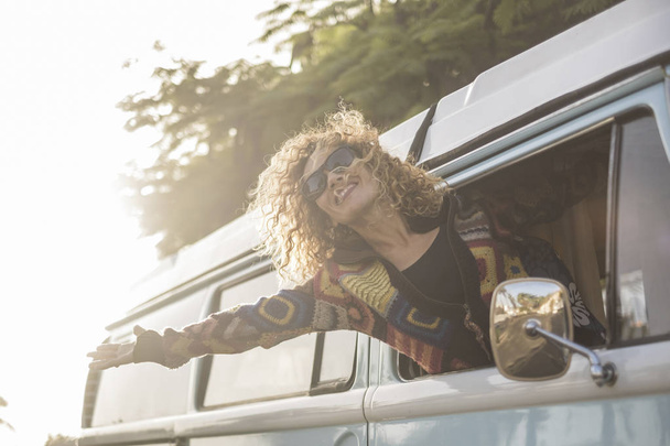 jonge vrouw uit voertuig genieten van wind tijdens reizen   - Foto, afbeelding