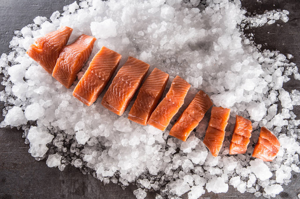 Salmon fillets portioned on ice and empty kitchen board - Top of view.  - Foto, imagen