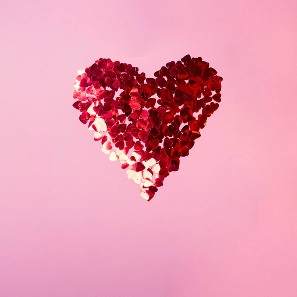 Valentine's day. Heart of red sequins on pink background - Фото, изображение