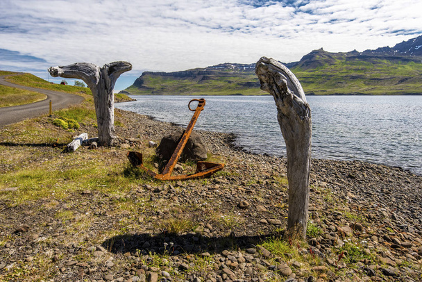 Bois flottants fixés verticalement et ancre ancienne à la frontière du Fjord Mjoifjordur, Islande orientale
 - Photo, image