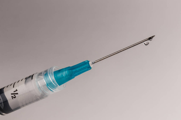 Nahaufnahme einer Spritze mit einer Nadel und einem Tröpfchen Flüssigkeit. Opiat- und Heroin-Überdosen sind in den letzten Jahren sprunghaft angestiegen. - Foto, Bild