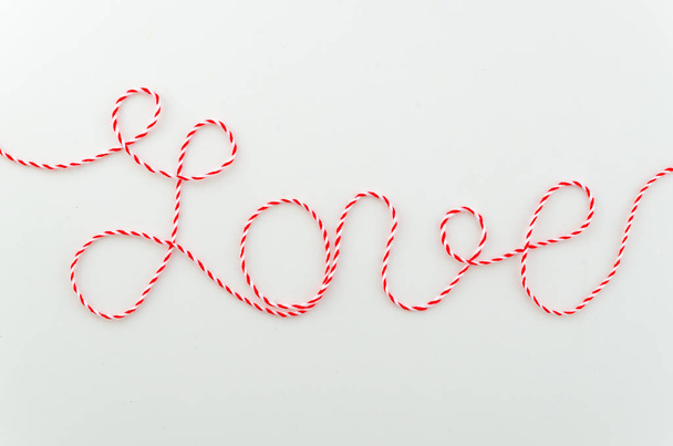 Love word written with double color white and red woolen thread lettering, concept and background for Valentines Day, copy space on white background - Photo, image
