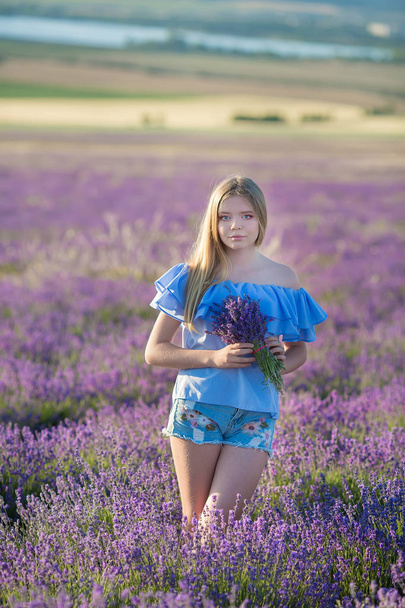 Smiling beautiful blond lady model on lavender field enjoy summer day wearing airy whit dress with bouquet of flowers - Foto, Imagen