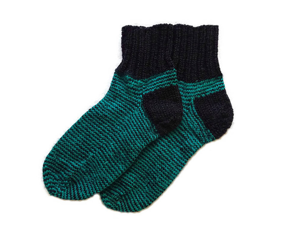 Un par de dos calcetines de invierno de lana caliente hechos a mano hechos a mano con rayas negras y verdes aislados en el fondo blanco
  - Foto, imagen
